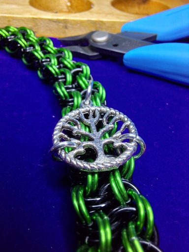 Black and green chainmail bracelet with the Tree of Life charm affixed on top.